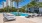 a pool with lounge chairs and palm trees by a building