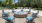 a group of chairs around a round fountain in a courtyard